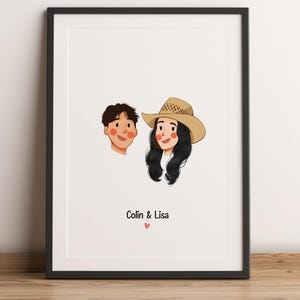 May include: Framed artwork with cartoon portraits of two people. One has dark hair, the other long black hair and a straw hat. Below the portraits is the text "Colin & Lisa" and a small pink heart. The background is white, and the frame is black.