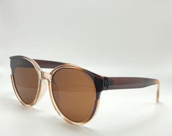 May include: Brown tortoise shell sunglasses with brown lenses. The sunglasses have a rounded frame and a thin, dark brown temple.