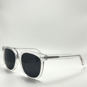 Puede incluir: Gafas de sol con montura transparente y lentes negras. Las gafas tienen una forma cuadrada clásica.