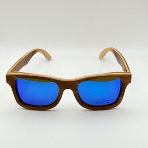 May include: Wooden-framed sunglasses with vibrant blue lenses. The frames have a natural wood grain finish, and the lenses provide UV protection. A stylish accessory for eye protection.