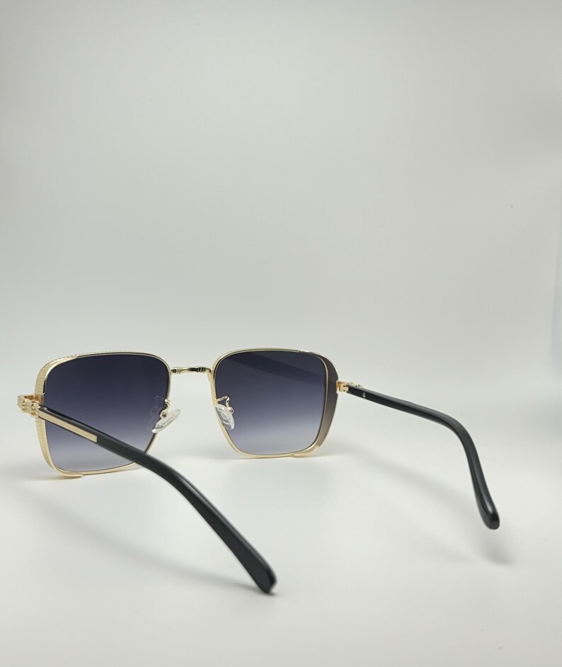 Peut inclure: Lunettes de soleil carr&eacute;es avec des montures noires et des verres gris fonc&eacute;. Les lunettes de soleil sont vues de l'arri&egrave;re.