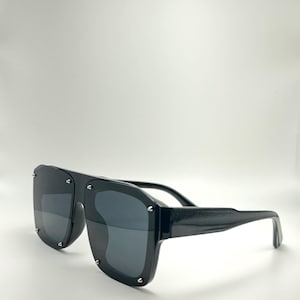 May include: Black square-shaped sunglasses with a thick black frame and dark lenses.