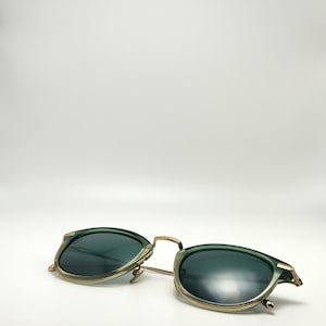 May include: Green and gold-toned sunglasses with a round frame.