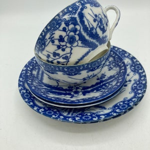 May include: A set of three blue and white porcelain teacups and saucers with a floral design. The cups and saucers are stacked on top of each other.