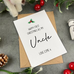 May include: White card with the text "Happy First Christmas as my Uncle" and a small holly sprig illustration. The card is signed "Love Esme x".