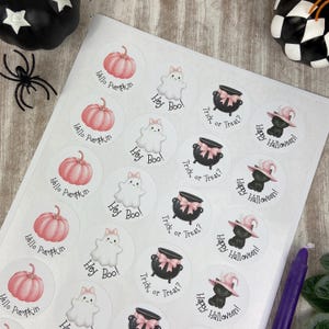 May include: Sheet of Halloween-themed stickers with various designs. Includes pink pumpkins with "Hello Pumpkin" text, white ghosts with "Hey Boo!", black cauldrons with "Trick or Treat?", and black cats with "Happy Halloween!"