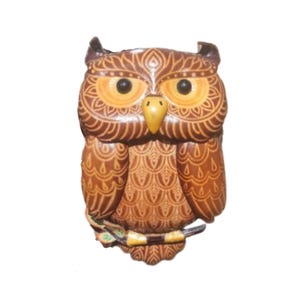 Könnte beinhalten: Braune Eulenfigur mit aufwendigen geätzten Mustern. Die Eule hat große gelbe Augen, einen gelben Schnabel und ein detailliertes Federdesign. Sie sitzt auf einem Ast mit grünen und gelben Akzenten und zeigt eine handwerkliche Ästhetik.