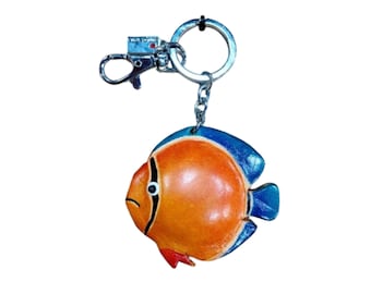 May include: A fish-shaped keychain with a silver clasp and ring. The fish is orange with blue fins and a black stripe. The keychain is a decorative accessory.