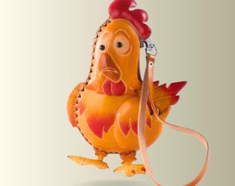 May include: A chicken-shaped leather coin purse in shades of orange, yellow, and red. The purse features a prominent red comb, a stitched edge, and a long, thin leather wrist strap attached to a metal clasp at the top of the chicken's head.