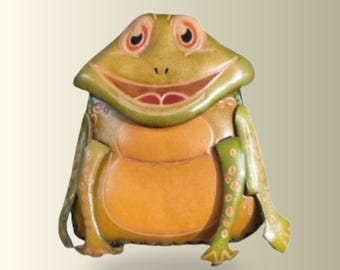 May include: A frog-shaped pouch featuring a green head with large eyes and a wide mouth, and a tan-colored belly. The limbs are green with light-colored spots, and the overall design is crafted with defined contours and a smooth, structured finish.