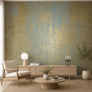 Könnte beinhalten: Eine Wandtapete mit einer strukturierten, abgenutzten Oberfläche in gedämpften Blau- und Metallic-Goldtönen. Das Design zeigt ein verwittertes, geschichtetes Erscheinungsbild mit vertikalen Streifen in Blattgoldoptik auf einem sanften blauen Grund.
