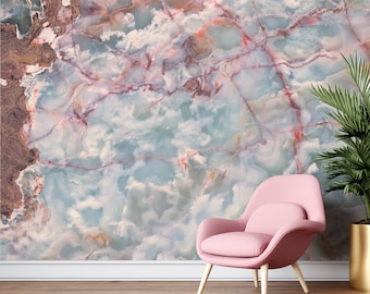May include: A pink armchair sits in front of a wall with a large abstract pattern of blue, white, and pink marble.