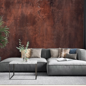 Könnte beinhalten: Ein graues Ecksofa mit verschiedenen Kissen steht vor einer rostigen roten Wand. Ein kleiner weißer Marmor-Couchtisch steht vor dem Sofa.