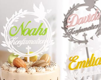 May include: Three white cake toppers with a wreath design and a dove. The toppers have the names "Noah's Confirmation", "Dawids Confirmation", and "Emilias Confirmation" written in green, pink, and yellow.