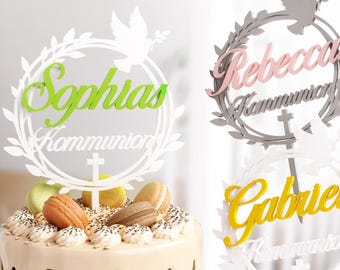 May include: Three white cake toppers with a wreath design, a dove, and a cross. The toppers are personalized with the names "Sophia", "Rebecca", and "Gabriel" and the text "Communion".