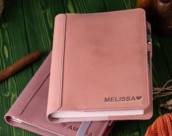 Peut inclure: Un carnet relié en cuir rose avec le nom "MELISSA" gravé sur la couverture. Le carnet est fermé et possède un porte-stylo sur le côté.