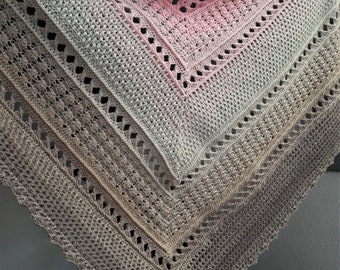 May include: A handmade crochet shawl in shades of pink, gray, and beige. The shawl features a detailed openwork design with a scalloped edge. The color gradient transitions from pink to gray to beige.