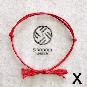 May include: Two red string bracelets with a tassel on each end. The bracelets are tied in a knot and have the text "SIRODDORI LONDON" printed on them.
