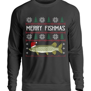 Peut inclure: Sweat-shirt noir à manches longues avec un motif festif "Merry Fishmas". Le graphisme représente un poisson portant un bonnet de Père Noël, des flocons de neige et des sapins. Le motif est rouge, blanc et vert.