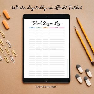 May include: A digital tablet displaying a printable blood sugar log with the text "Blood Sugar Log" in pink and white. The tablet is on a brown surface with yellow pencils, orange erasers, and gold and silver paper clips.