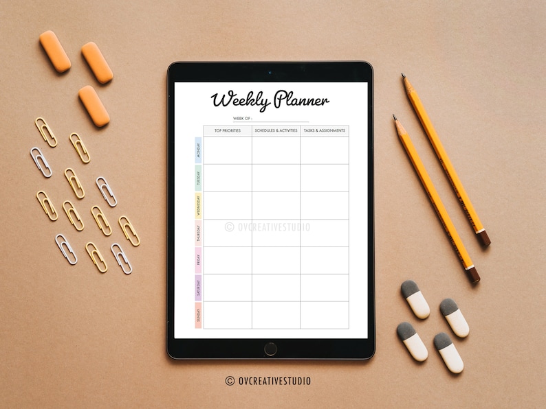 May include: A weekly planner on a tablet screen with a white background. The planner has columns for top priorities, schedules and activities, and tasks and assignments. The tablet is on a brown surface with pencils, erasers, and paper clips.