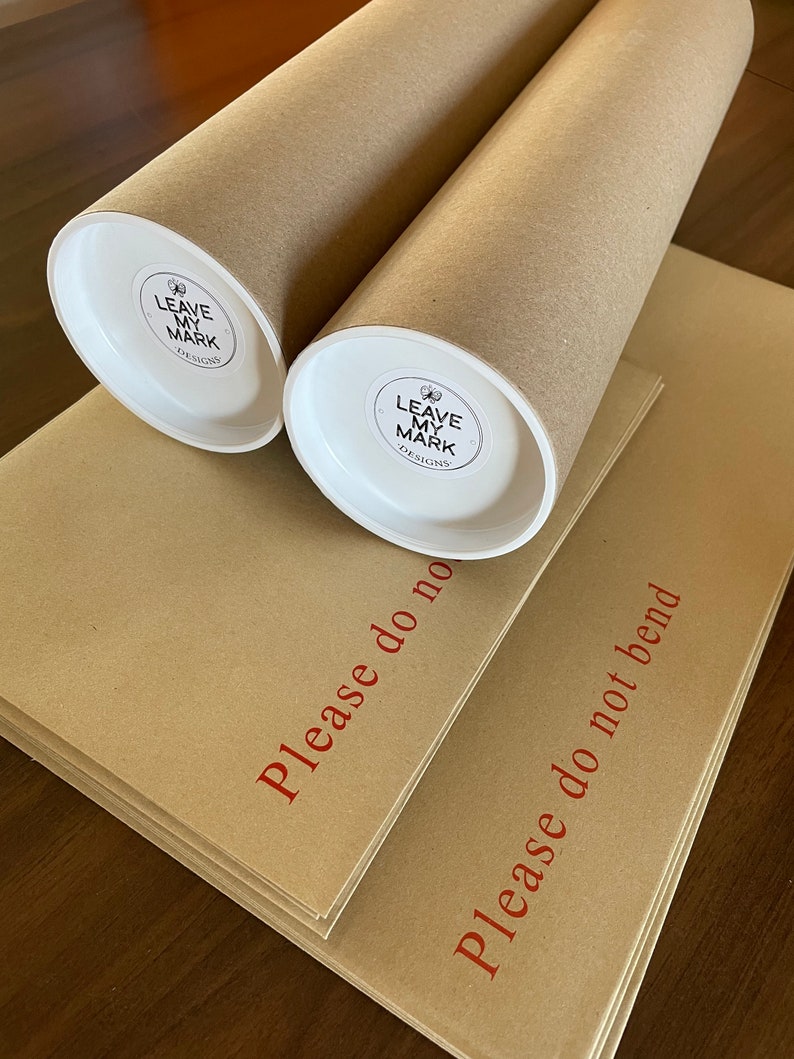 May include: Two brown cardboard tubes with white end caps. The end caps have a white sticker with a black logo that says "Leave My Mark Designs". The tubes are stacked on top of each other. The tubes are on top of two brown cardboard envelopes. The envelopes have red text that says "Please do not bend".