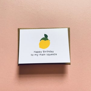 May include: A white card with a yellow lemon illustration and the text "Happy Birthday to my main squeeze".