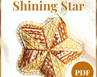 May include: Handmade holiday felt ornament in the shape of a star. The star is cream-colored with intricate embroidery in shades of brown and yellow. The text "Shining Star" is displayed above the ornament.