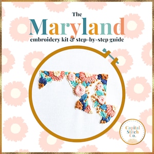 May include: Embroidered floral design of the state of Maryland in a hoop. The embroidery is done in shades of pink, blue, green, and gold. The text "The Maryland embroidery kit & step-by-step guide" is at the top of the image. The text "Capital Stitch Co." is at the bottom of the image.