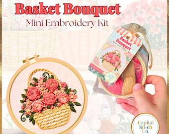 May include: A mini embroidery kit featuring a basket of pink flowers. The kit includes a hoop, embroidery floss, and a needle. The packaging has the text "Basket Bouquet Mini Embroidery Kit".