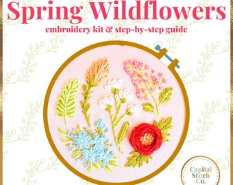 Puede incluir: Kit de bordado con un aro sobre un fondo rosa y flores silvestres bordadas de colores. El kit incluye una guía paso a paso y se titula "The Spring Wildflowers" con el logotipo "Capital Stitch Co."