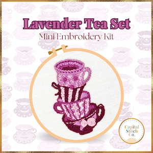 May include: A mini embroidery kit featuring a stack of three lavender teacups, with a pink and purple floral design, in a white embroidery hoop. The kit is titled "Lavender Tea Set" and is labeled "Mini Embroidery Kit".