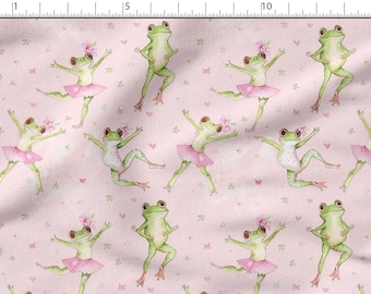 May include: A pink fabric with a repeating pattern of green frogs wearing pink tutus and flowers in their hair. The frogs are in various dance poses. The background is a light pink with small white stars and hearts.
