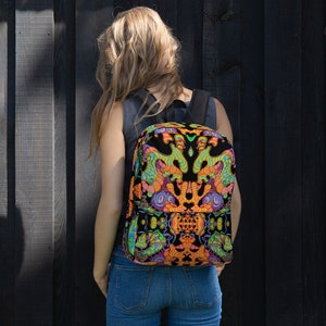 May include: A black backpack with a colourful psychedelic pattern featuring orange, yellow, green, and blue colours. The pattern is symmetrical and features abstract shapes.