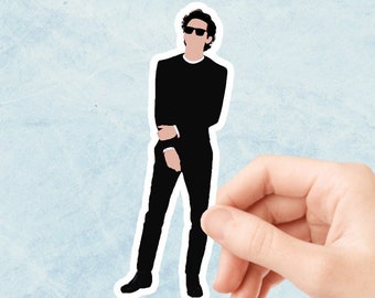 May include: A black and white illustration of a person wearing sunglasses and a black outfit. The person is standing with their arms crossed.
