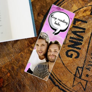 May include: Pink and grey bookmark featuring a photo of two men and a speech bubble that says "Keep reading, babe."