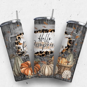 May include: Three stainless steel tumblers with lids and straws. The tumblers are wrapped with a design featuring a rustic wood background, leopard print, fall leaves, and pumpkins. The middle tumbler has the text "Hello Pumpkin" on it.