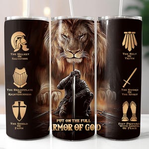 Puede incluir: Tres vasos negros con un diseño que presenta un león, un caballero arrodillado y las palabras "PUT ON THE FULL ARMOR OF GOD". Cada vaso muestra ilustraciones y texto dorados relacionados con la armadura de Dios.