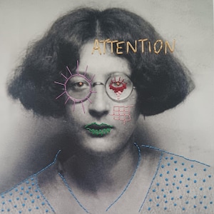 Può includere: Fotografia in bianco e nero di una donna con dettagli ricamati. La parola "ATTENTION" è ricamata sopra la sua testa. Il suo viso presenta accenti ricamati, tra cui un sole, un occhio e una griglia. Le sue labbra sono verdi.