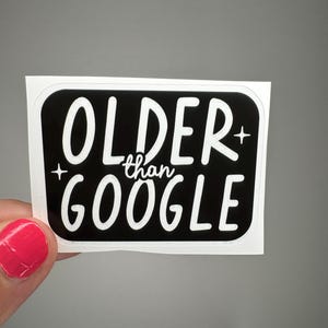 May include: A black and white sticker with the text "OLDER than GOOGLE". The text is in a bold, sans-serif font. The sticker has a black background with a white border.