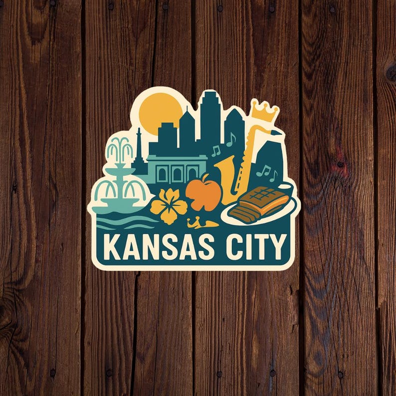 Puede incluir: Una colorida pegatina con un dise&ntilde;o de Kansas City. El dise&ntilde;o incluye un paisaje urbano, un sol, una fuente, un saxof&oacute;n, una manzana y el texto "KANSAS CITY". La pegatina est&aacute; sobre un fondo de madera.