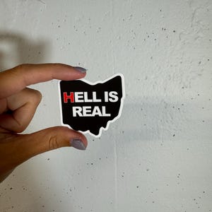 May include: A black and white sticker shaped like the state of Ohio with the text "HELL IS REAL" in red and white letters.