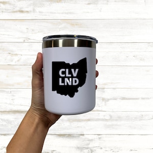 May include: White stainless steel travel mug with a black outline of the state of Ohio and the text "CLV LND" inside the outline.