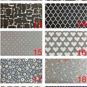 May include: A collection of ten fabric swatches featuring various patterns including horizontal lines, white daisies on black, geometric blocks, quatrefoil, white polka dots, white hearts, small floral prints, grey chevrons, and white diamonds on navy.