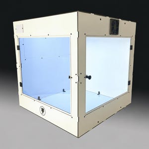 May include: A square 3D printer enclosure featuring off-white panels, clear acrylic side and front panels, a black cooling fan mounted on the top frame, and a small black circular logo on the lower front panel with a black door handle.