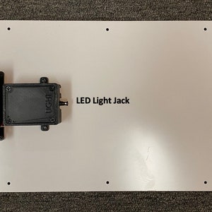May include: A white metal panel with a black exhaust fan and a black LED light jack. The text "LED Light Jack" and "Exhaust Fan" are printed on the panel.