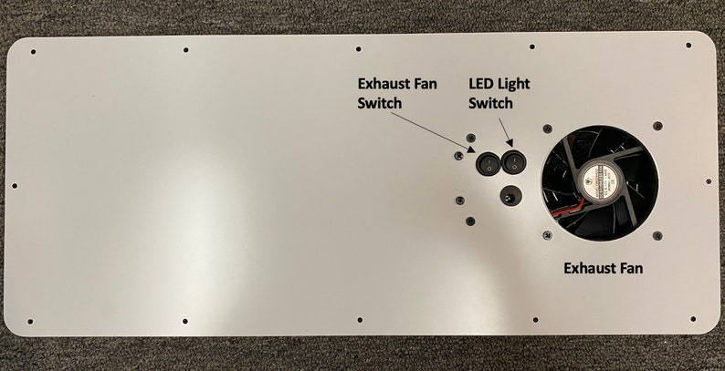 May include: White metal panel with two black toggle switches labeled "Exhaust Fan Switch" and "LED Light Switch". A black fan is mounted on the right side of the panel with the text "Exhaust Fan" below it.