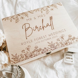 May include: A wooden box with a floral design and the text "Mr & Mrs Birchall Royle Forest Weddings 14th October 2023".