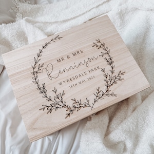 May include: A wooden box with an engraved floral design and the text "MR & MRS  Jenningson  WYRESDALE PARK  18TH MAY 2023".