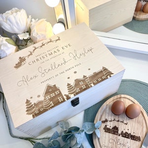 May include: A wooden box with a Christmas Eve design, personalised with the name "Alex Stallard-Heslop". The box is decorated with a snowy village scene and the text "Special Delivery for the Attention of... Property of the North Pole".
